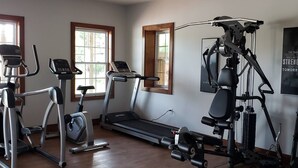 Et hjemmegym med løbebånd, crosstrainere og en vægtbænk.