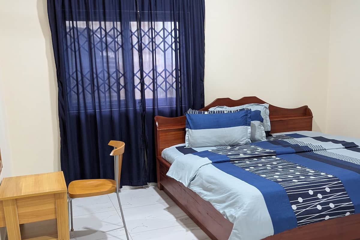 A bedroom with a wooden bed, a small wooden table, and a chair.
