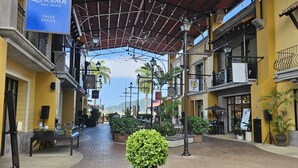 A covered outdoor area with a sign for 'Los Suenos Real Estate Sales Office,' potted plants, and a brick pathway.