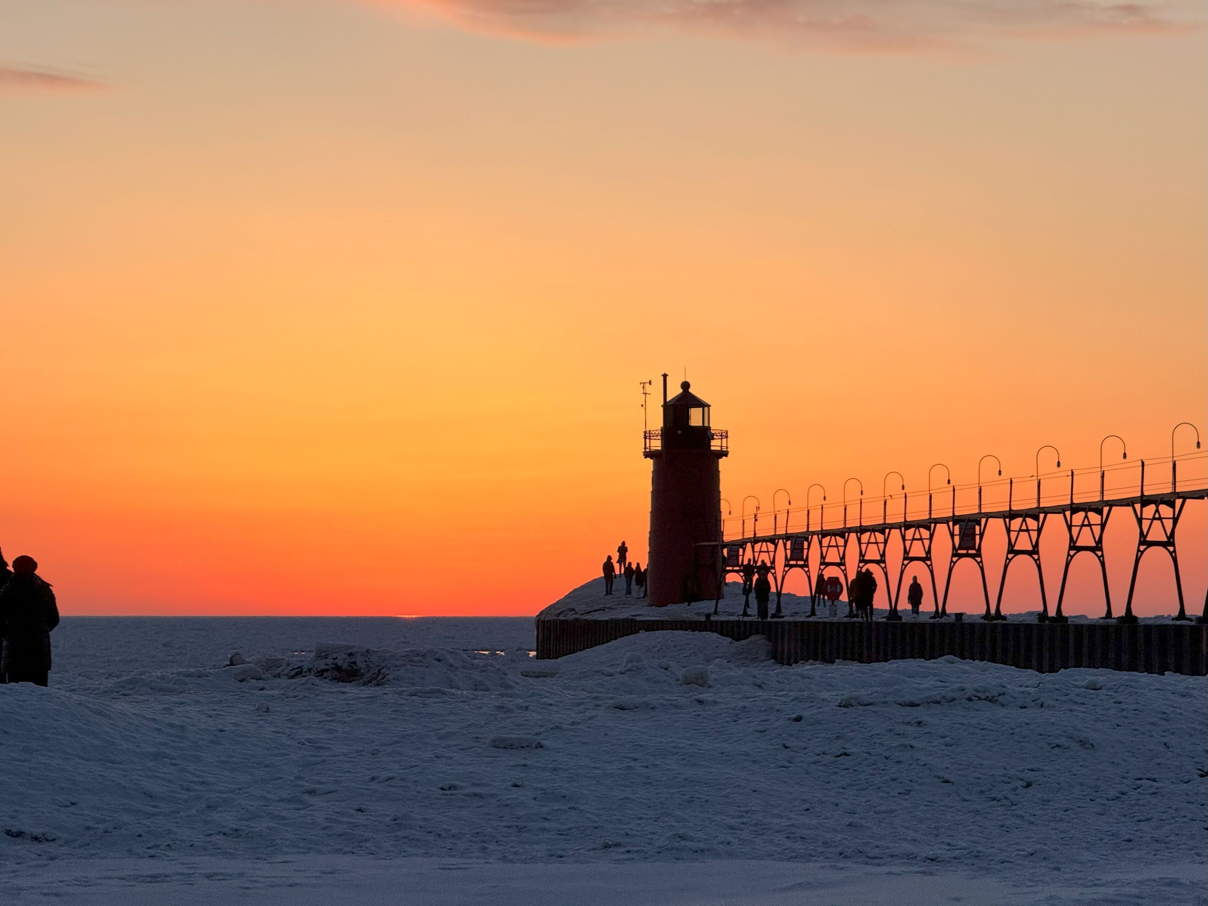 Ein Leuchtturm bei Sonnenuntergang mit einem Metallweg, der zu ihm führt.