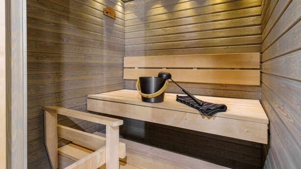 Una sauna amb seients de fusta, un cubell i una tovallola.
