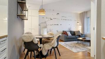 Una sala de estar moderna con un sofá gris, una mesa de comedor con sillas y un espejo grande en la pared.