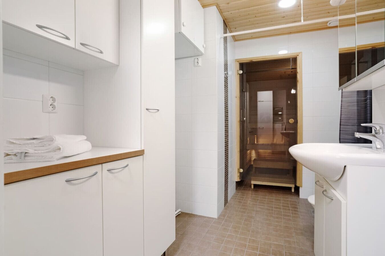 A modern bathroom with white cabinetry, a wooden countertop, and a sink with a mirror.