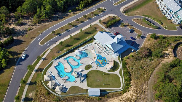 An aerial view of a resort with a swimming pool, lounge chairs, and a parking area. - 2 BR Condo with shared pool and central air (Kill Devil Hills)