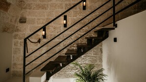 A staircase with wooden steps and black railings, leading up to a stone wall with a potted plant at the bottom. - Archè Luxury Private Spa Suite in Polignano a Mare with Breakfast Included (Polignano a Mare)