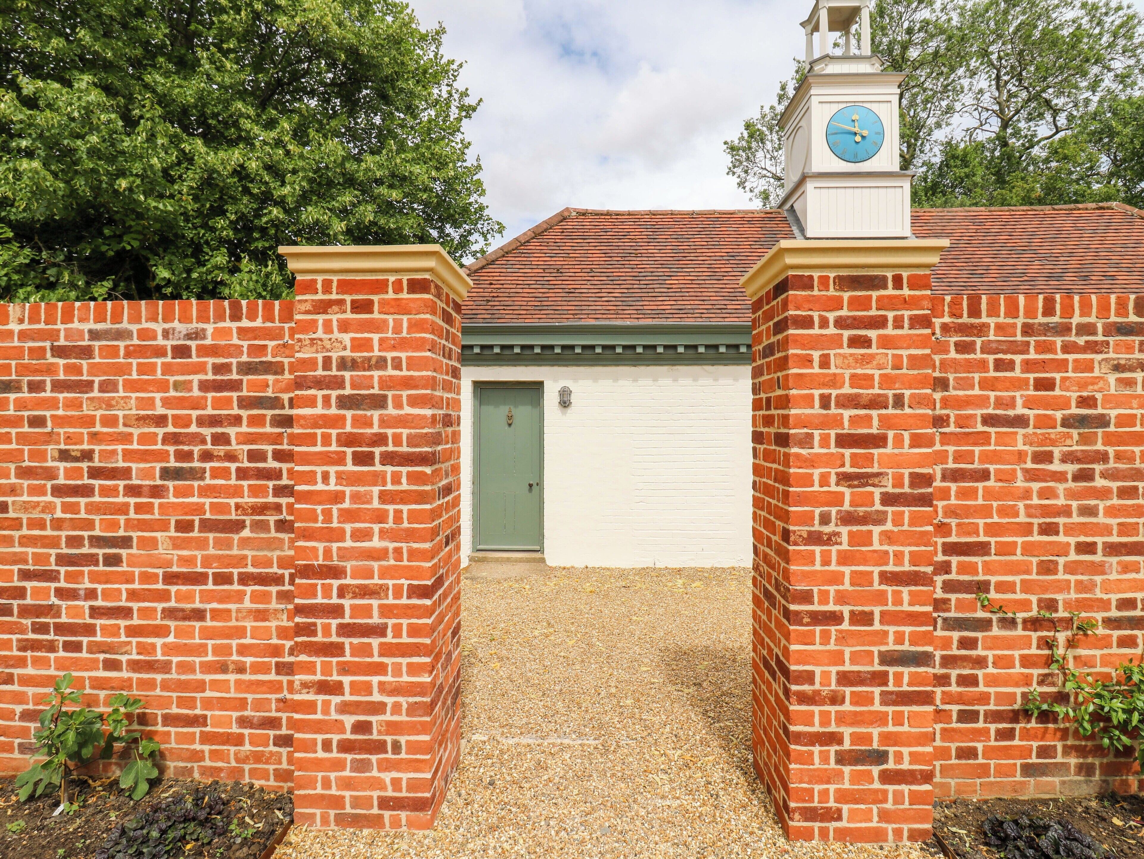 A brick wall with a white garage door and a clock tower.