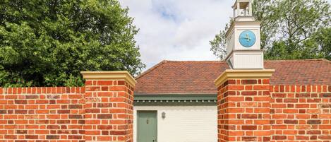 A brick wall with a white garage door and a clock tower.