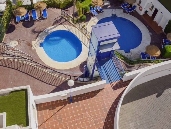 A rooftop pool area with a circular pool, sun loungers, and a staircase leading to a deck. - Cubo's Beach Side Los Patos Apartment & Parking / community pool / close to the beach / air conditioning / free Wi-Fi (Benalmádena)