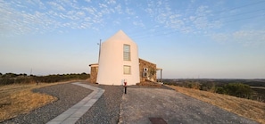 Um edifício com fachada branca, base de pedra e uma entrada com calçada.