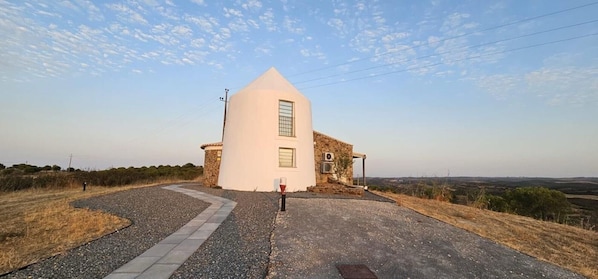 Un edificio con facciata bianca, base in pietra e vialetto lastricato che vi conduce.