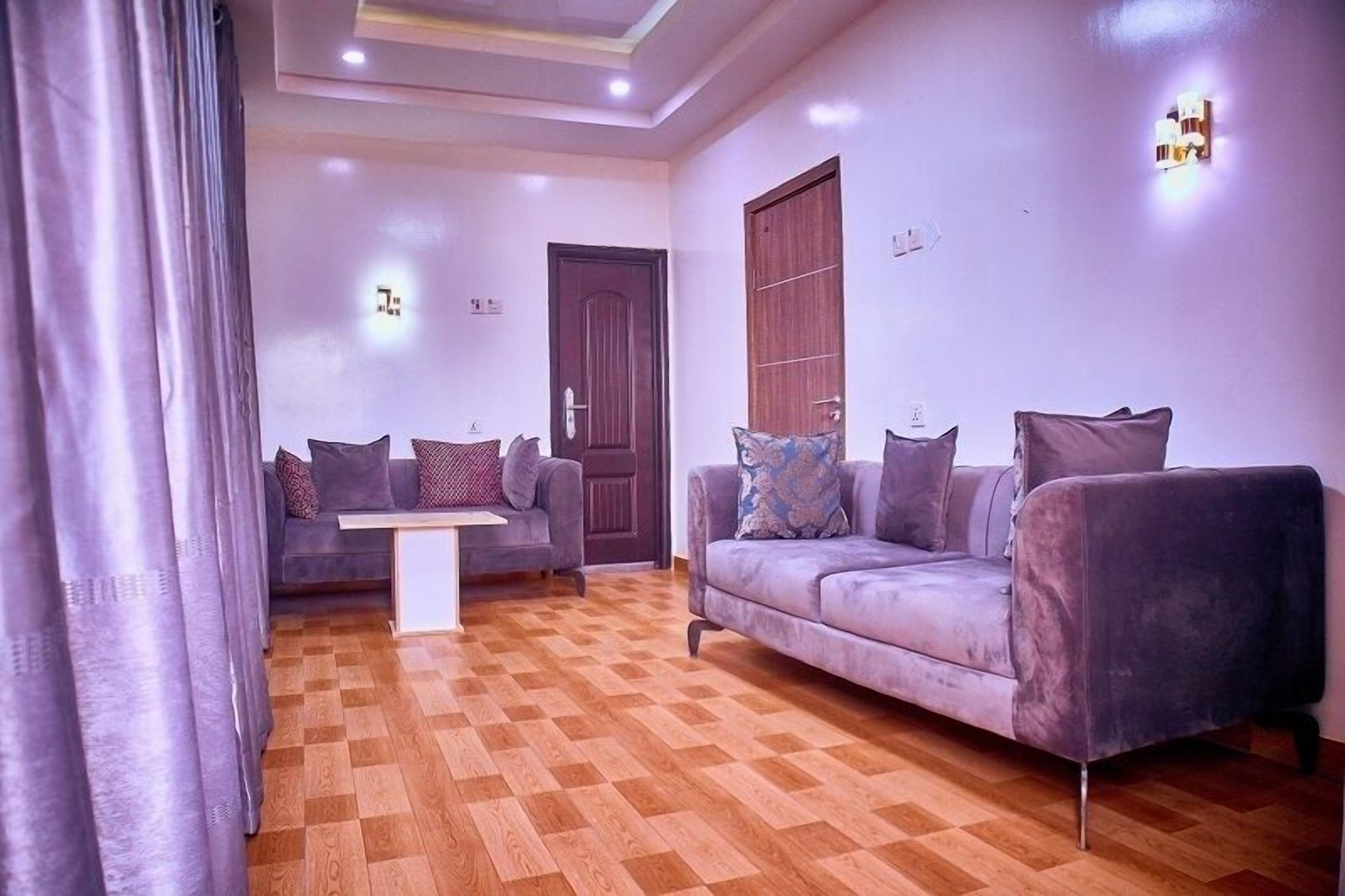 A living room with a checkered wooden floor, two sofas with cushions, a coffee table, and a door.