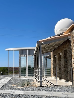 A modern building with a glass facade, stone exterior, and a dome structure.