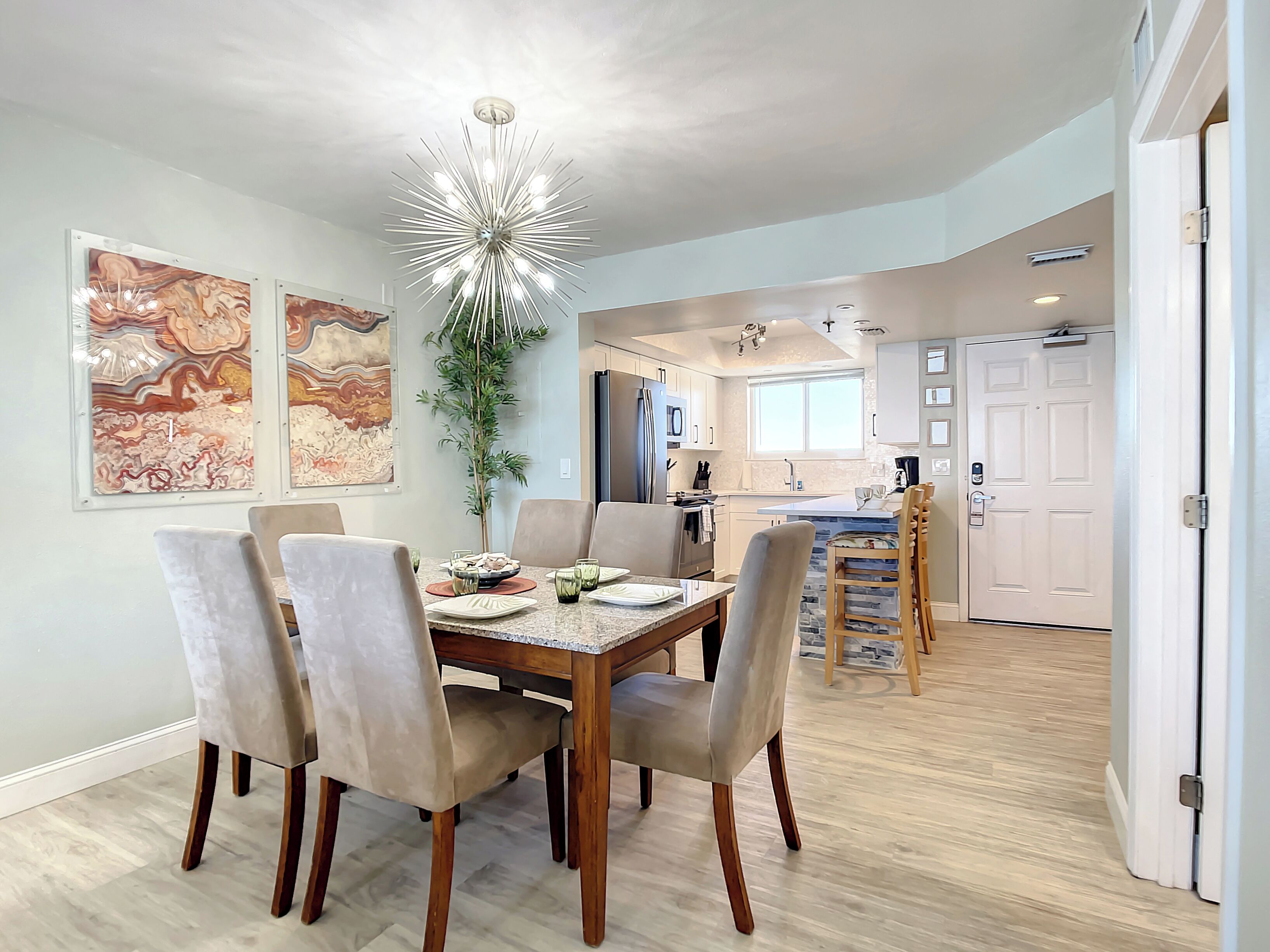 A modern dining area with a wooden table and chairs, a decorative ceiling light, and abstract wall art.