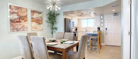 A modern dining area with a wooden table and chairs, a decorative ceiling light, and abstract wall art.