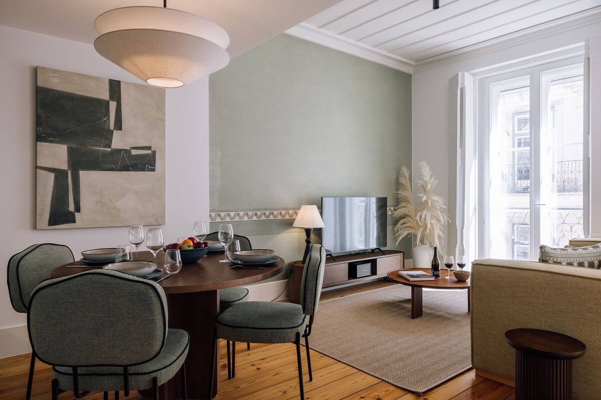 A modern dining area with a round table, chairs, and a television.