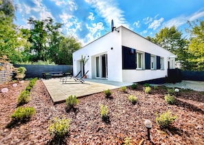 A modern house with a patio, a satellite dish, and a small garden.