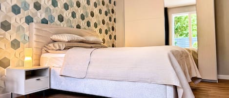 Un dormitorio con cama, mesita de noche y pared con un diseño geométrico.