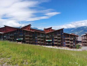 Um edifício moderno com várias varandas e vista para montanhas.