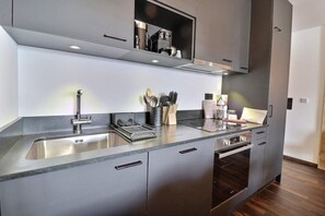 A modern kitchen with a stainless steel sink, a built-in oven, and a countertop with kitchen utensils.