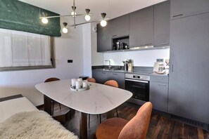 A modern kitchen with grey cabinets, a built-in oven, and a coffee machine.