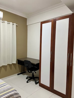 Una habitación con cama, escritorio y armario.