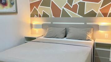 Ein Schlafzimmer mit einem Bett, zwei Nachttischen, einer Wand mit geometrischem Muster und einem Bild an der Wand.