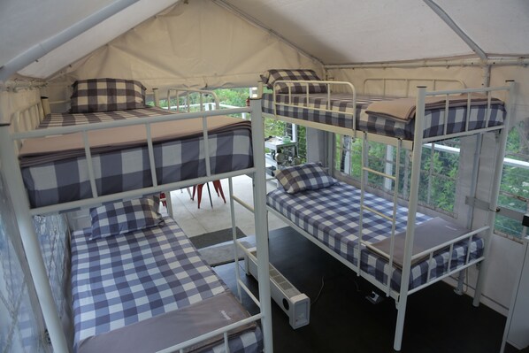 A multi-level bunk bed room with checkered bedding, a heater, and a view of greenery outside. - Iglam Ijen (Banyuwangi)