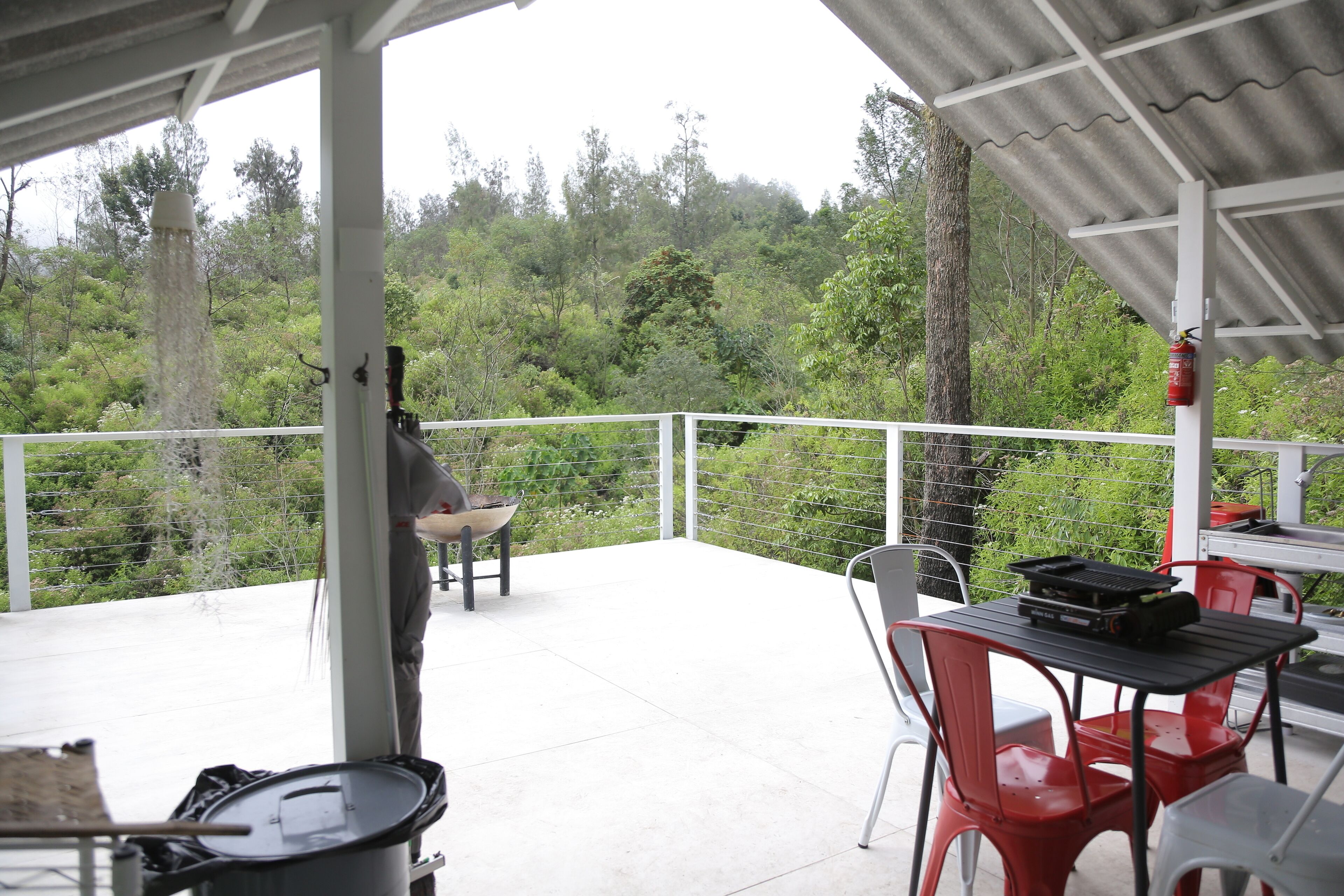 A covered outdoor area with a table and chairs, a grill, and a fire extinguisher.