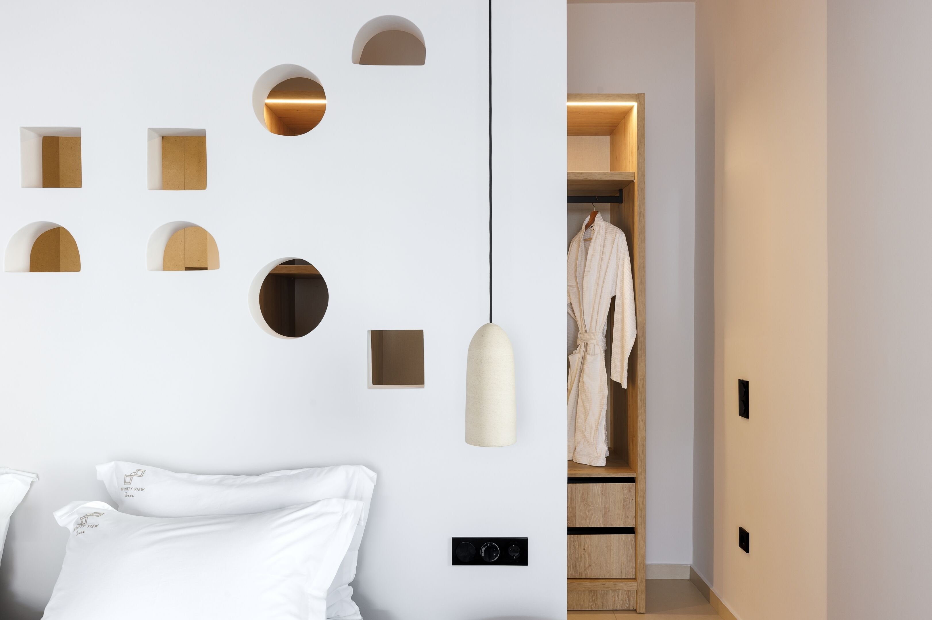 Ein zeitgemäßes Schlafzimmer mit Bett, Kleiderschrank und Pendelleuchte.