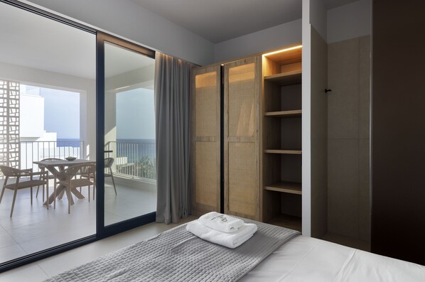 Habitació d'hotel moderna amb balcó, un llit amb tovallola blanca ben estovada i un armari de fusta.