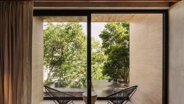 A room with a large glass door leading to a balcony with two chairs and a table.
