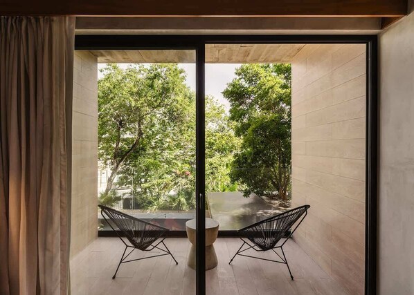 A room with a large glass door leading to a balcony with two chairs and a table.