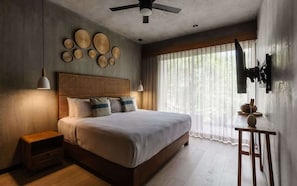 A bedroom with a bed, bedside tables, a ceiling fan, and a window with curtains.