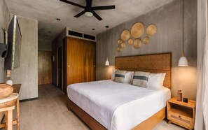 A modern bedroom with a large bed, wooden headboard, bedside tables, and a ceiling fan. - Terramar Viento Apartment Beach Club Access (Tulum)