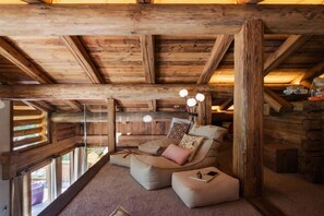 A cozy log cabin interior with a sofa, cushions, and a small table. - Chalet, view panoramic/mountain, terrace, balcony, fireplace or stove, parking, tv, 317m², La Clusaz (La Clusaz)
