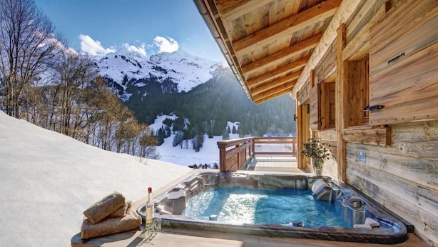 Une cabane en bois avec un jacuzzi et une terrasse en bois.