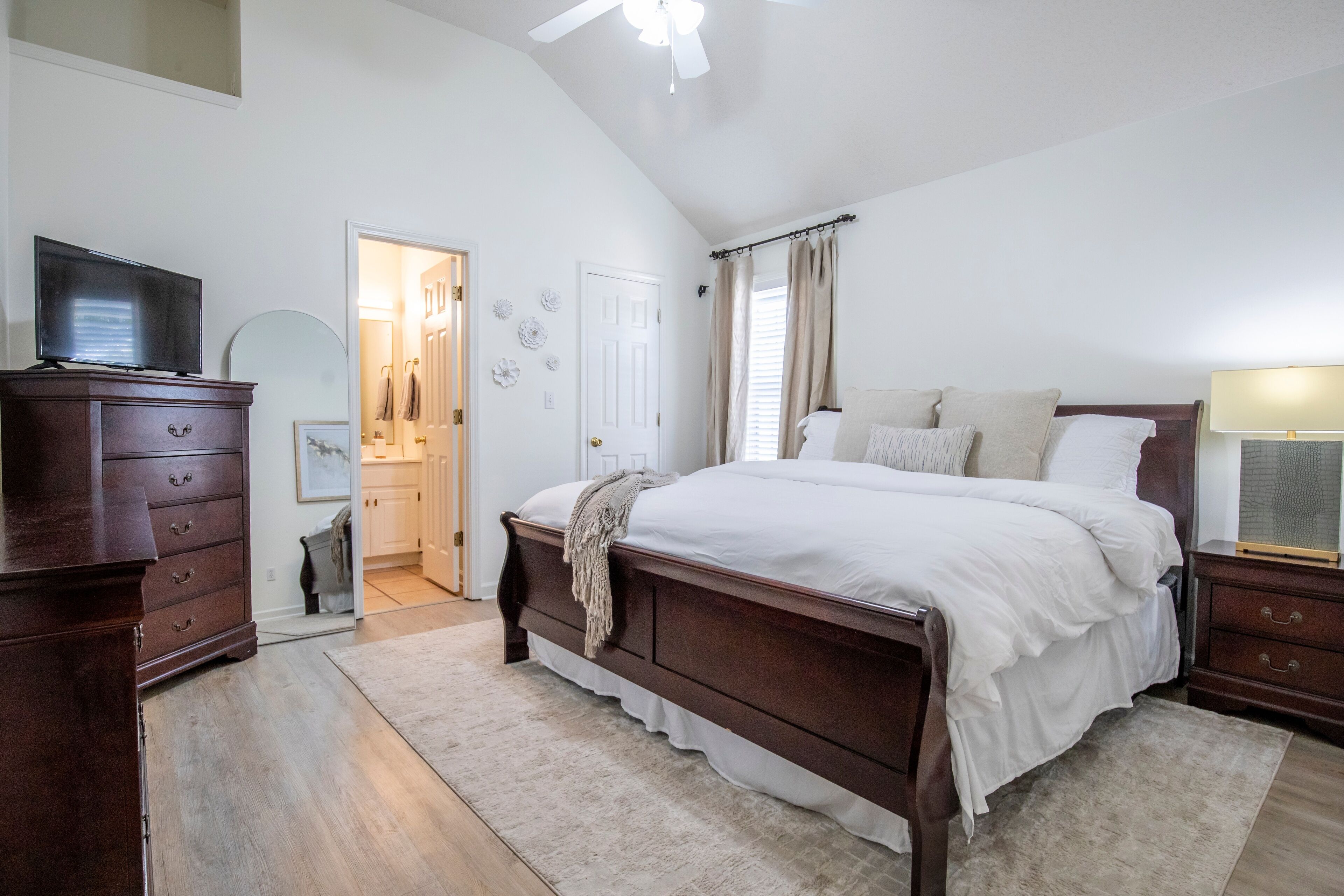A bedroom with a wooden bed, a TV, a dresser, and a ceiling fan. - The Pappy, 2BR House by Velvet Ditch Villas (Oxford)