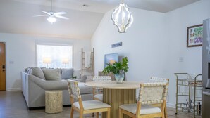 A dining area with a round wooden table, four chairs, a vase with a plant, and a chandelier. - The Pappy, 2BR House by Velvet Ditch Villas (Oxford)