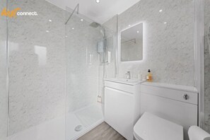 Un baño moderno con ducha envuelta en vidrio, un lavabo blanco y un inodoro.
