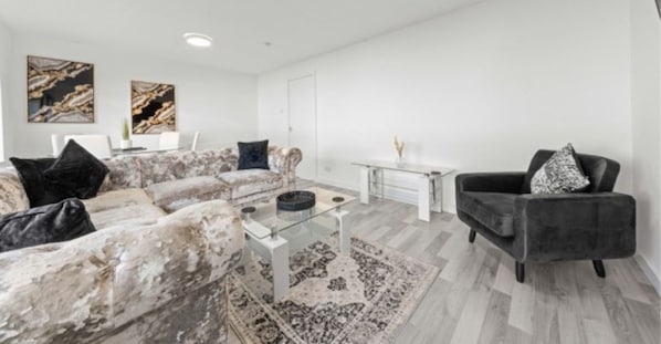 Una sala de estar moderna con un sofá de mármol, una mesa de centro de vidrio y un sillón oscuro.