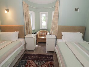 A bedroom with two beds, a small sofa, and a nightstand. - Boxbush Lodge (Monmouth)