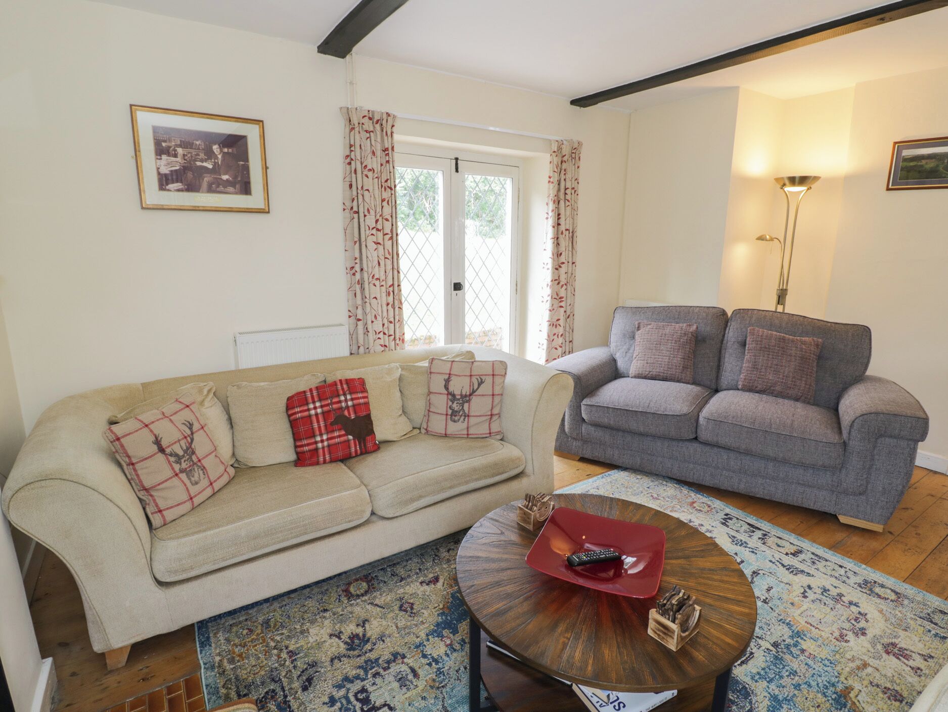 A living room with a beige sofa, a grey sofa, a round coffee table, and a patterned rug.