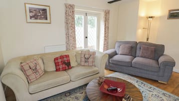 A living room with a beige sofa, a grey sofa, a round coffee table, and a patterned rug.