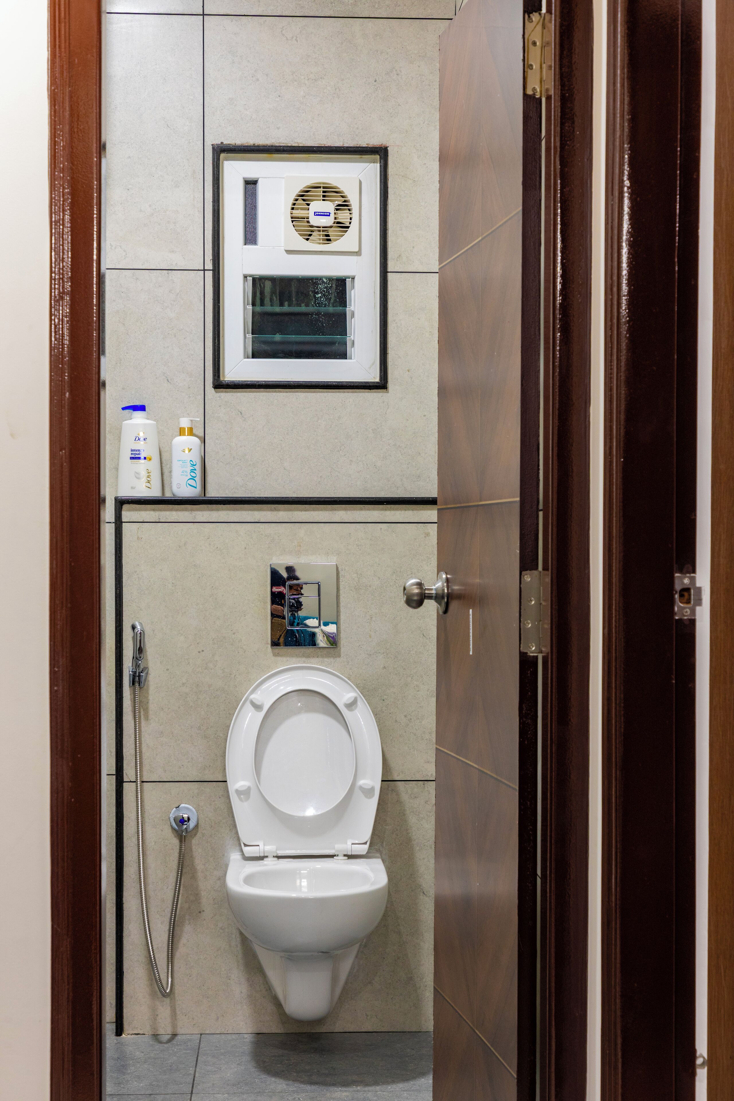 Un baño con inodoro, secamanos y dos botellas de Dove.