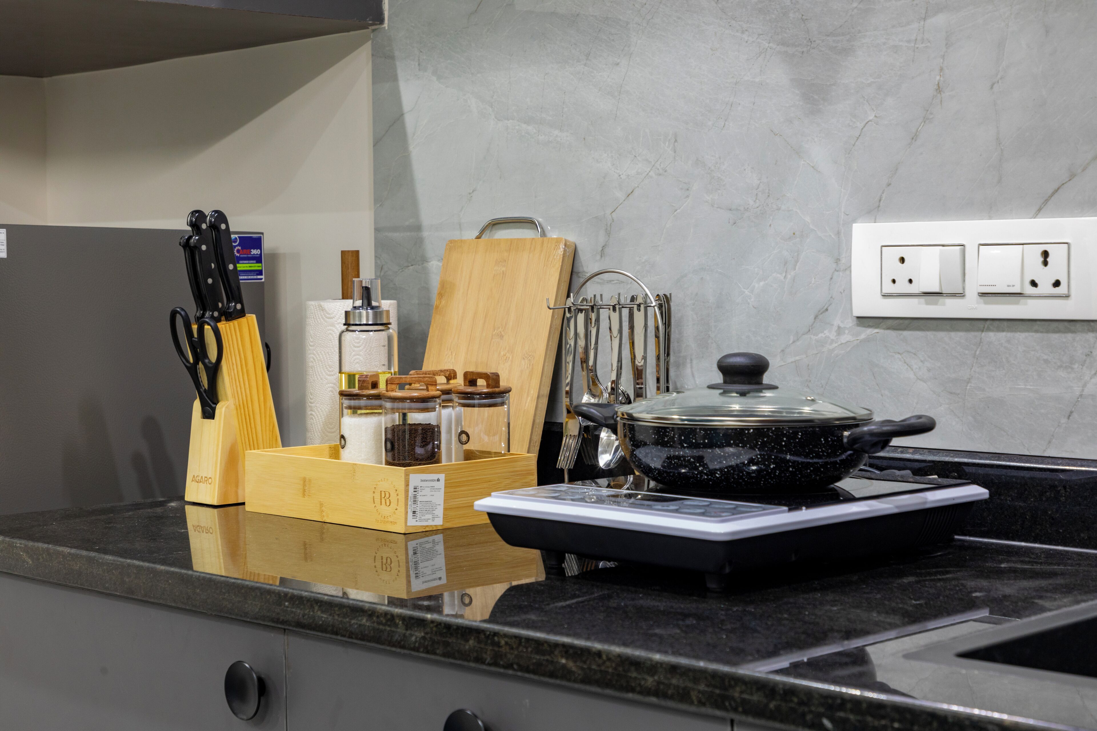 A kitchen counter with a stove, a cutting board, a knife set, and a spice rack.