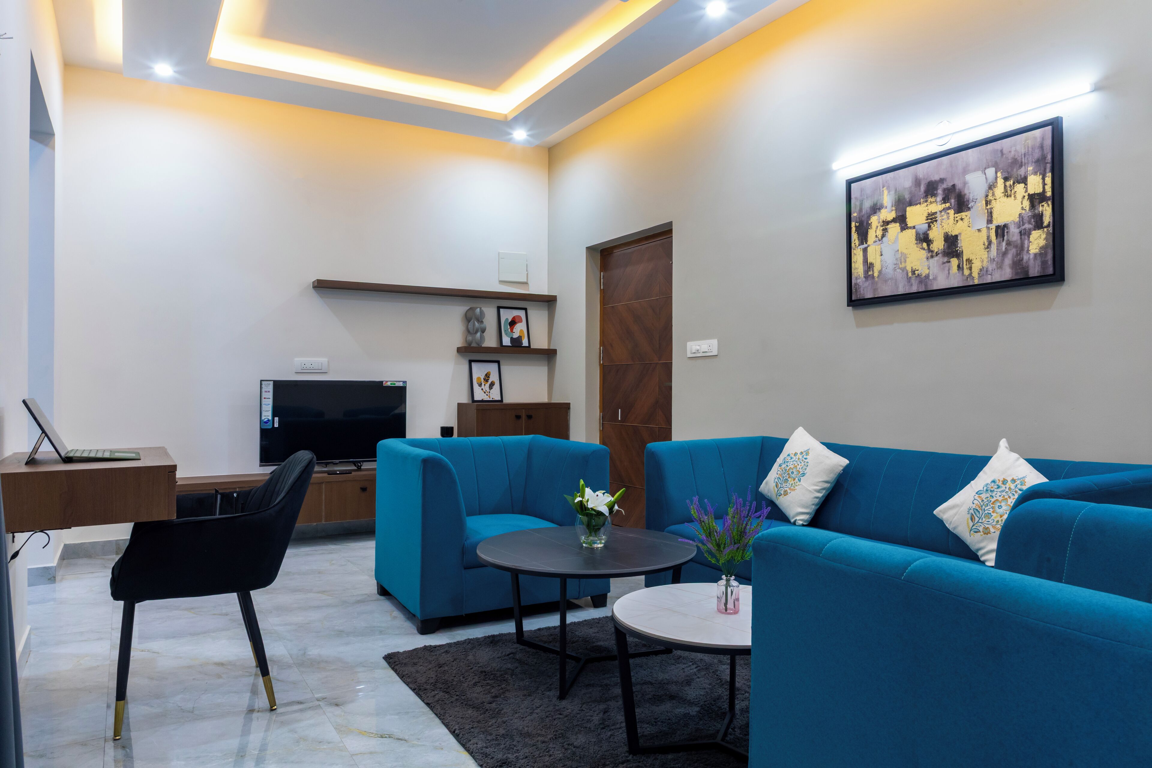 Un salon moderne avec un canapé bleu, une table basse ronde et un téléviseur à écran plat.
