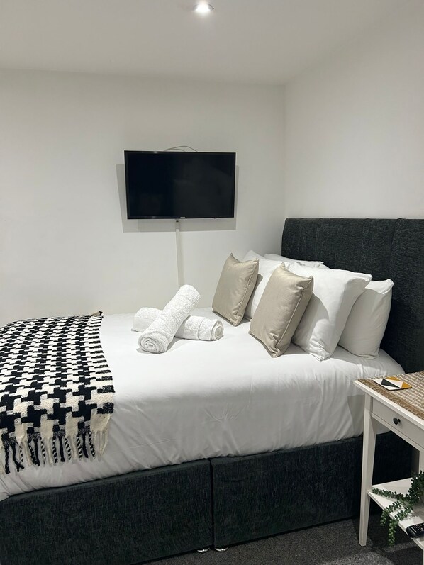 A modern hotel room with a bed, a TV mounted on the wall, and a bedside table with a remote control. - Flat 2 - Eign St. Hereford (Herefordshire)
