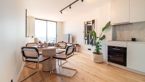 A modern kitchen with a dining area, wooden flooring, and a large window.