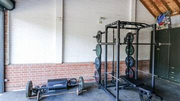 A gym with weightlifting equipment, a brick wall, and a wooden ceiling.