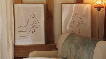 Una habitación con sofá, dos cuadros enmarcados, una lámpara y paneles de madera.